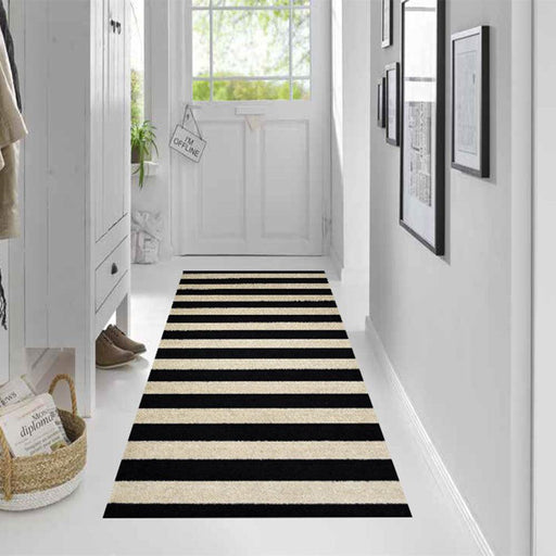 Farmhouse Stripe Black and Sand striped rug on a white floor in a hallway with a door and wall decorations.