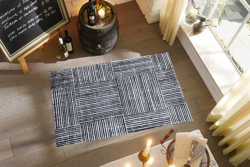 Patterned rug on a wooden floor with candles and a chalkboard in the background