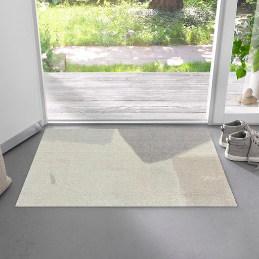 Beige rug on a gray floor with a garden view through a window.