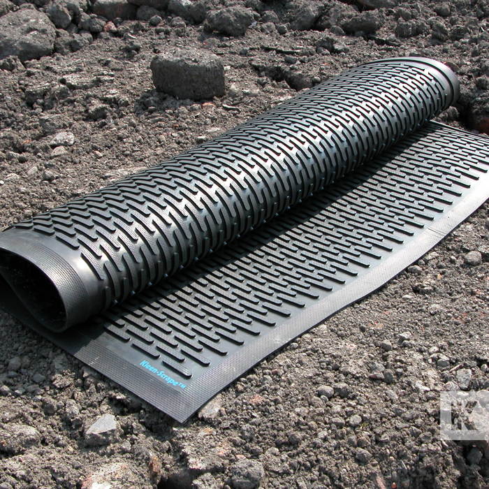 Roll of black scraper mat on a gravel surface